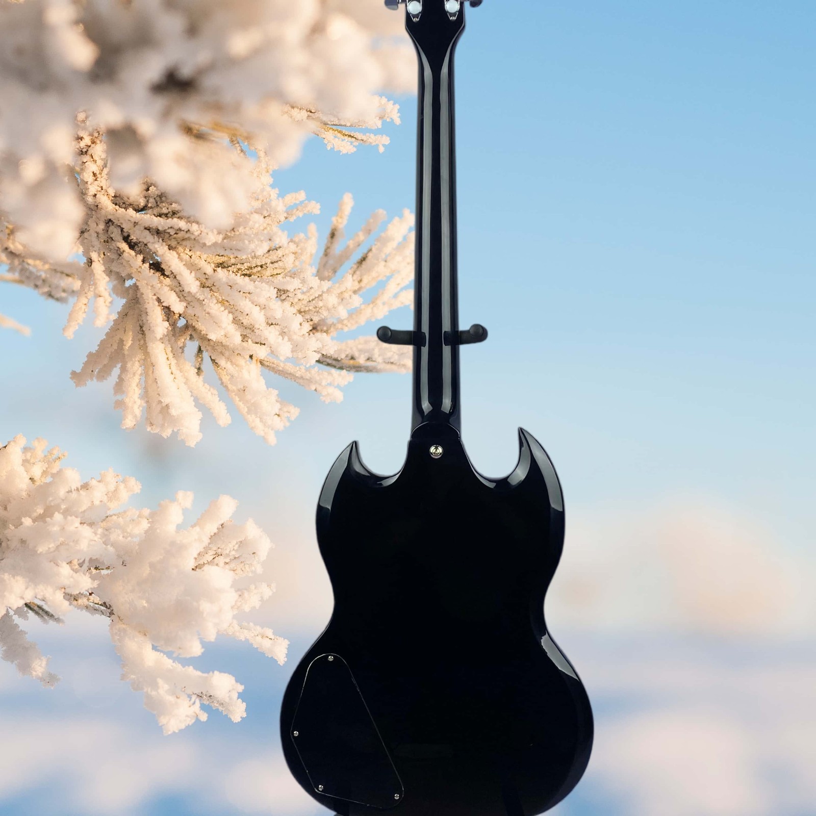 Black electric guitar with black protective cover and cross-shaped inlay.
