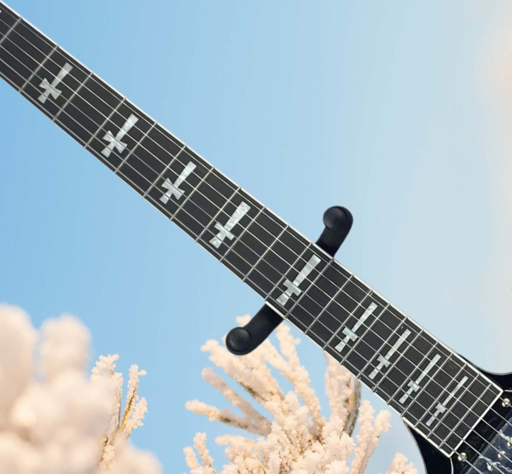 Black electric guitar with black protective cover and cross-shaped inlay.