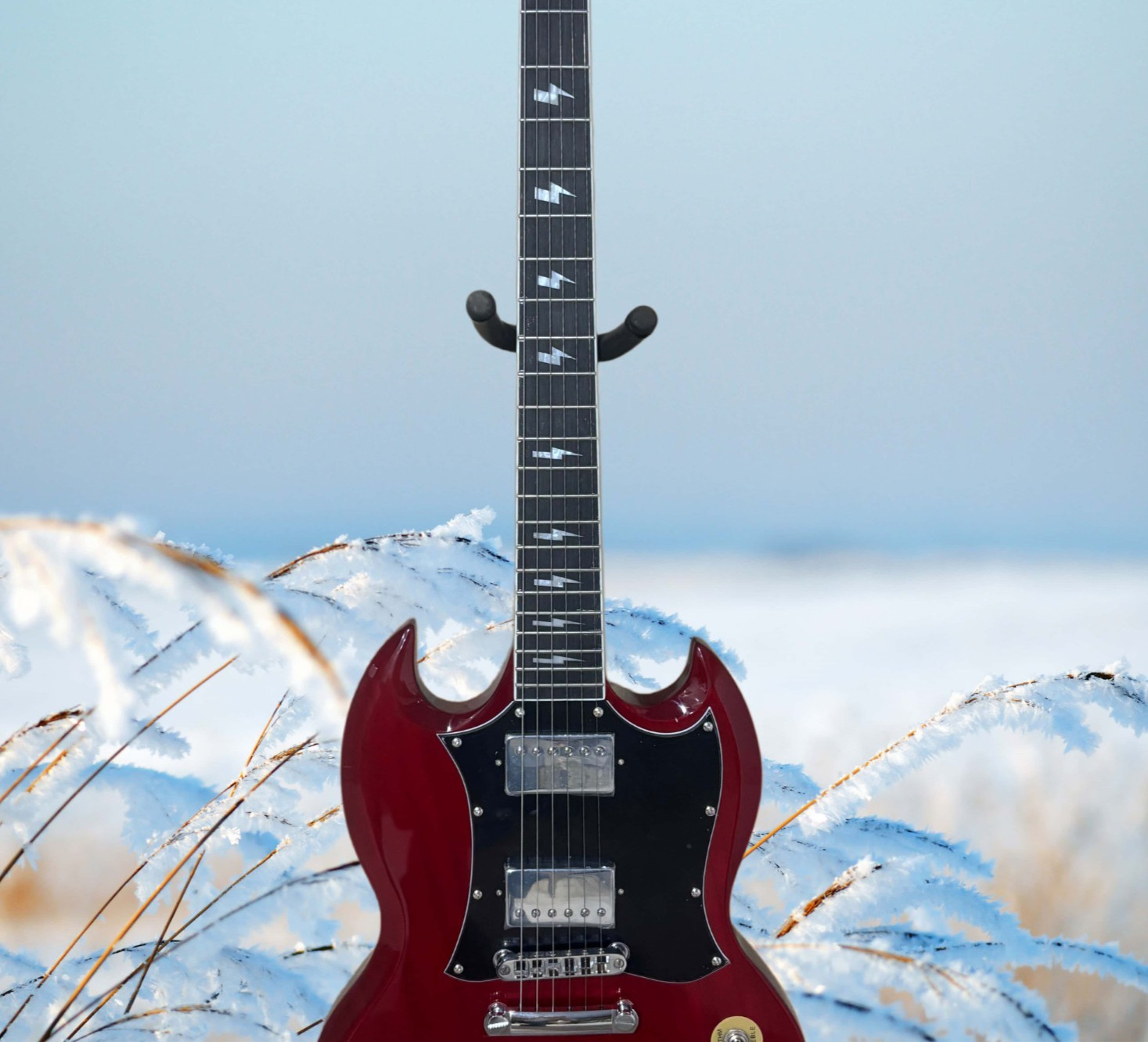 Burgundy electric guitar with a black pickguard and lightning-shaped inlays